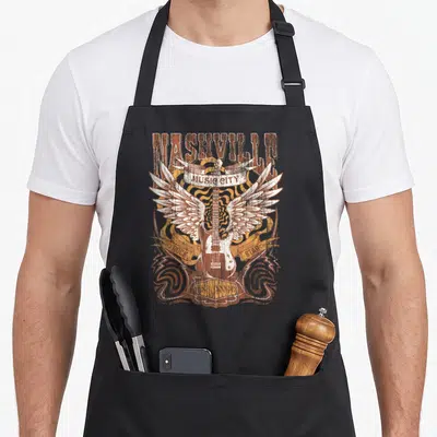Guitarist country apron - Winged electric guitar with Nashville Music City Rock Star Tennessee text in distressed brown — shown on a black cotton canvas apron against a white background