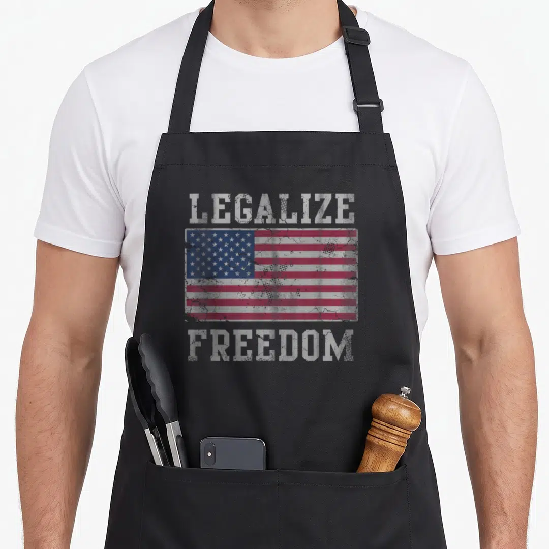 Legalize american flag apron - Distressed USA flag centered between LEGALIZE and FREEDOM text in red white blue — shown on a black cotton canvas apron against a white background