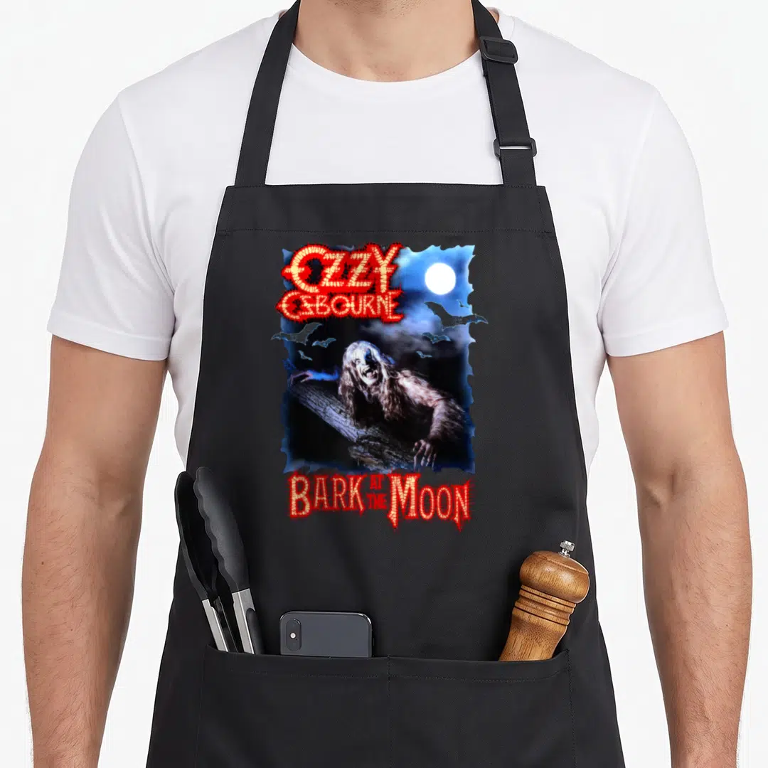 Batm ozzy osbourne apron - Werewolf on log under moon with flying bats and OZZY OSBOURNE text — shown on a black cotton canvas apron against a white background