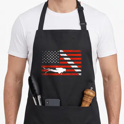 Diver american flag apron - White scuba diver silhouette on distressed red and white American flag pattern — shown on a black cotton canvas apron against a white background