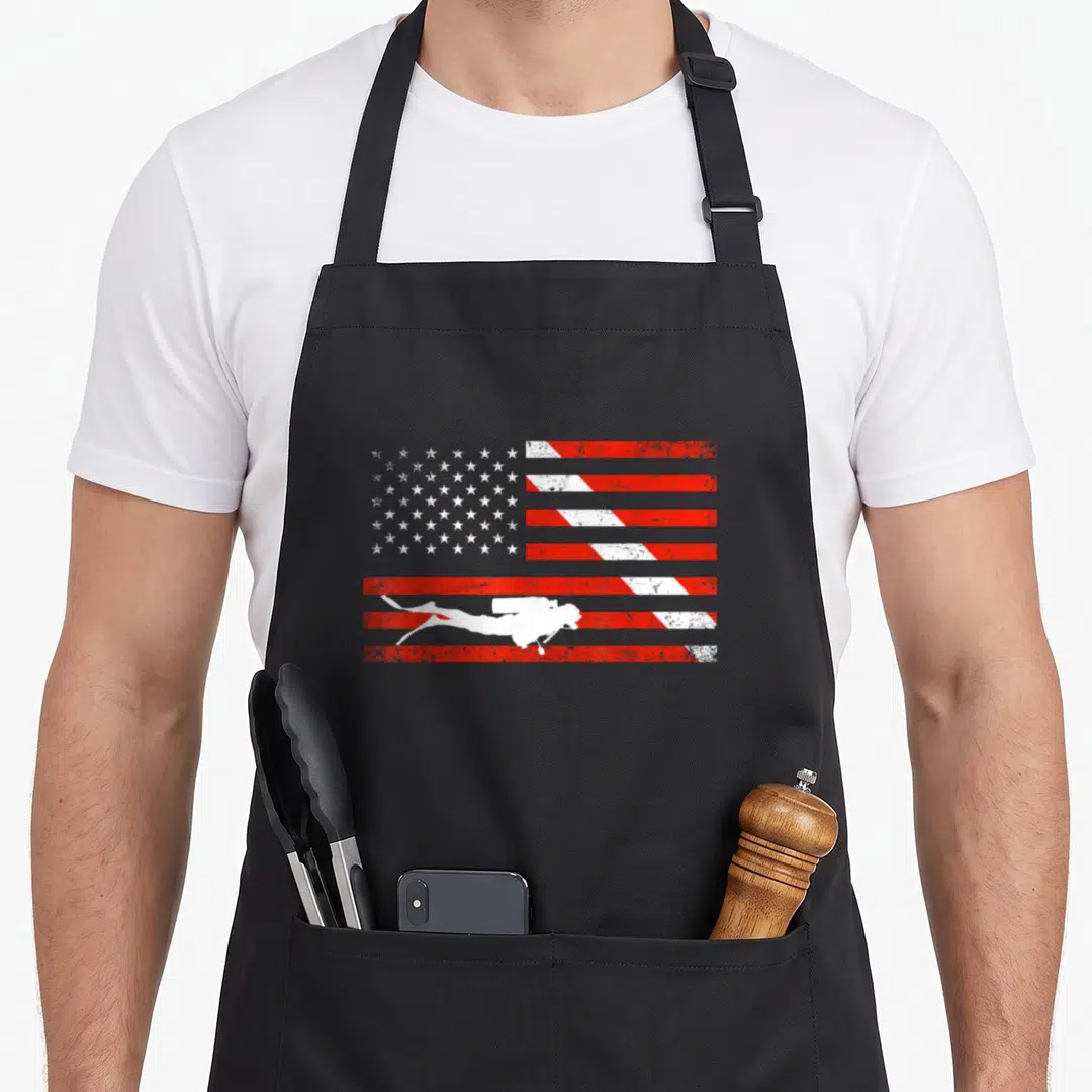 Diver american flag apron - White scuba diver silhouette on distressed red and white American flag pattern — shown on a black cotton canvas apron against a white background