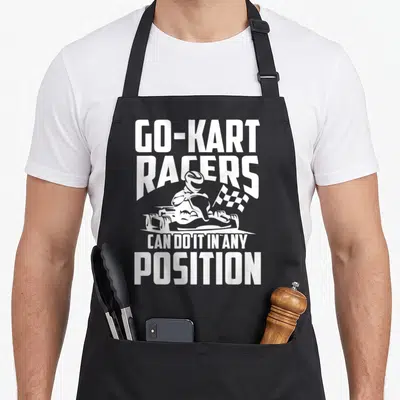 Position racing apron - White GO-KART RACERS text with minimalist kart driver and checkered flag graphic — shown on a black cotton canvas apron against a white background