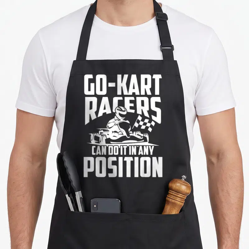 Position racing apron - White GO-KART RACERS text with minimalist kart driver and checkered flag graphic — shown on a black cotton canvas apron against a white background