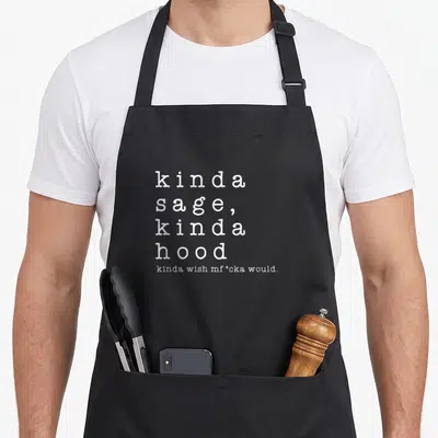 Kinda sage apron - White stacked text reading kinda sage kinda hood with a censored wish on grey background — shown on a black cotton canvas apron against a white background