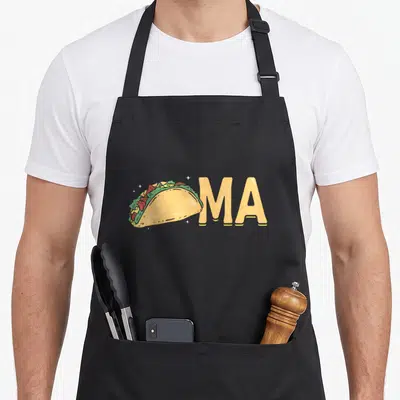 Washington taco apron - Cartoon taco illustration next to yellow MA text with white sparkles — shown on a black cotton canvas apron against a white background