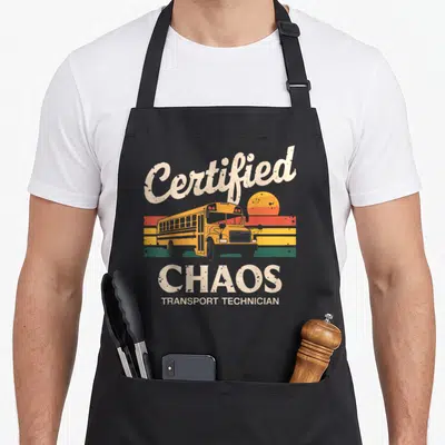 Certified chao apron - Retro school bus graphic with arched Certified Chaos Transport Technician text over colored — shown on a black cotton canvas apron against a white background