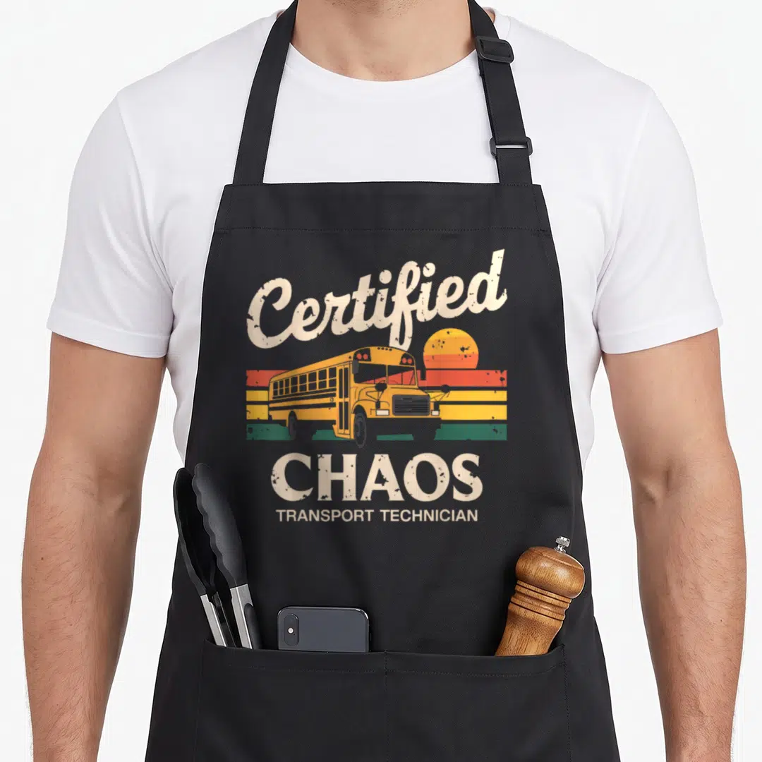 Certified chao apron - Retro school bus graphic with arched Certified Chaos Transport Technician text over colored — shown on a black cotton canvas apron against a white background