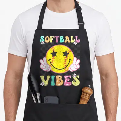 Softball game aprons - Retro smiley softball with peace hands and SOFTBALL VIBES text on checkerboard — shown on a black cotton canvas apron against a white background