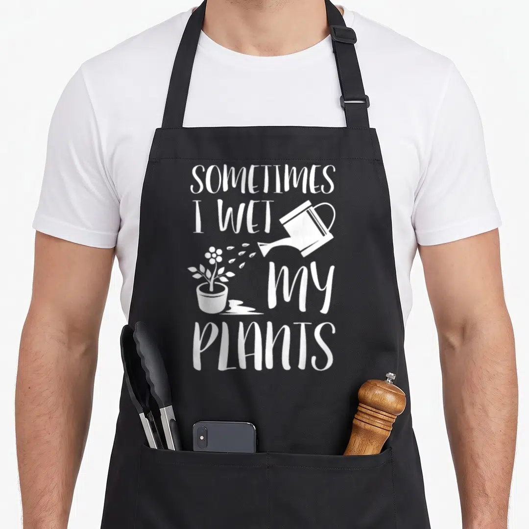 Sometime gardener apron - White stacked text reading SOMETIMES I WET MY PLANTS next to a watering can pouring water — shown on a black cotton canvas apron against a white background