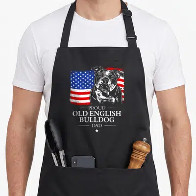 Proud english american flag apron - Bulldog portrait over distressed red white blue flag with stacked text PROUD OLD — shown on a black cotton canvas apron against a white background