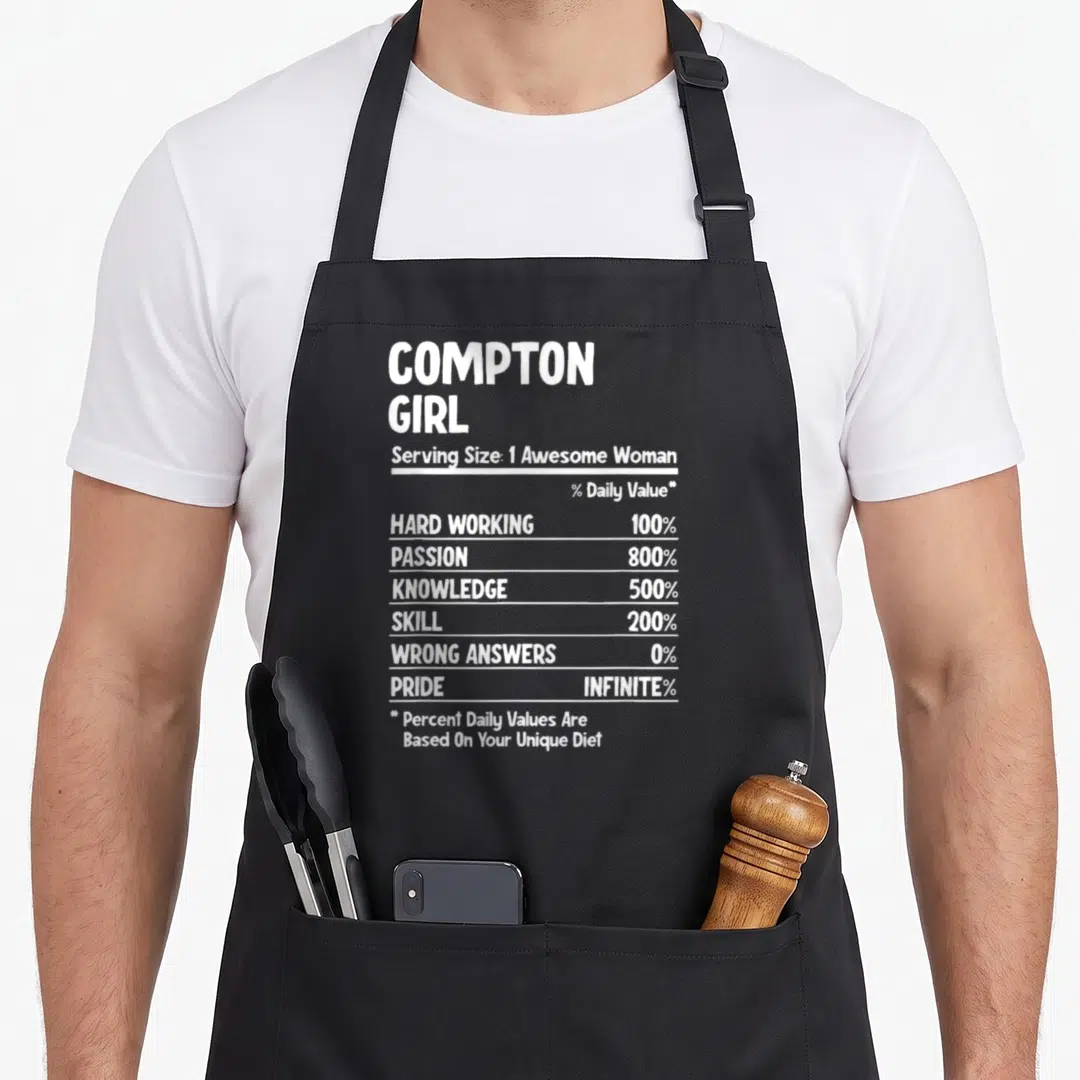 Funny compton apron - White nutrition facts label text on black apron reading Compton Girl with stats like 100% hard — shown on a black cotton canvas apron against a white background
