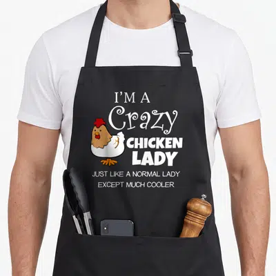Farmyard chicken apron - Cartoon hen with red comb and white text I'm a crazy chicken lady — shown on a black cotton canvas apron against a white background