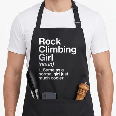 Rock sassy apron - White stacked text defining Rock Climbing Girl as a noun just much cooler — shown on a black cotton canvas apron against a white background
