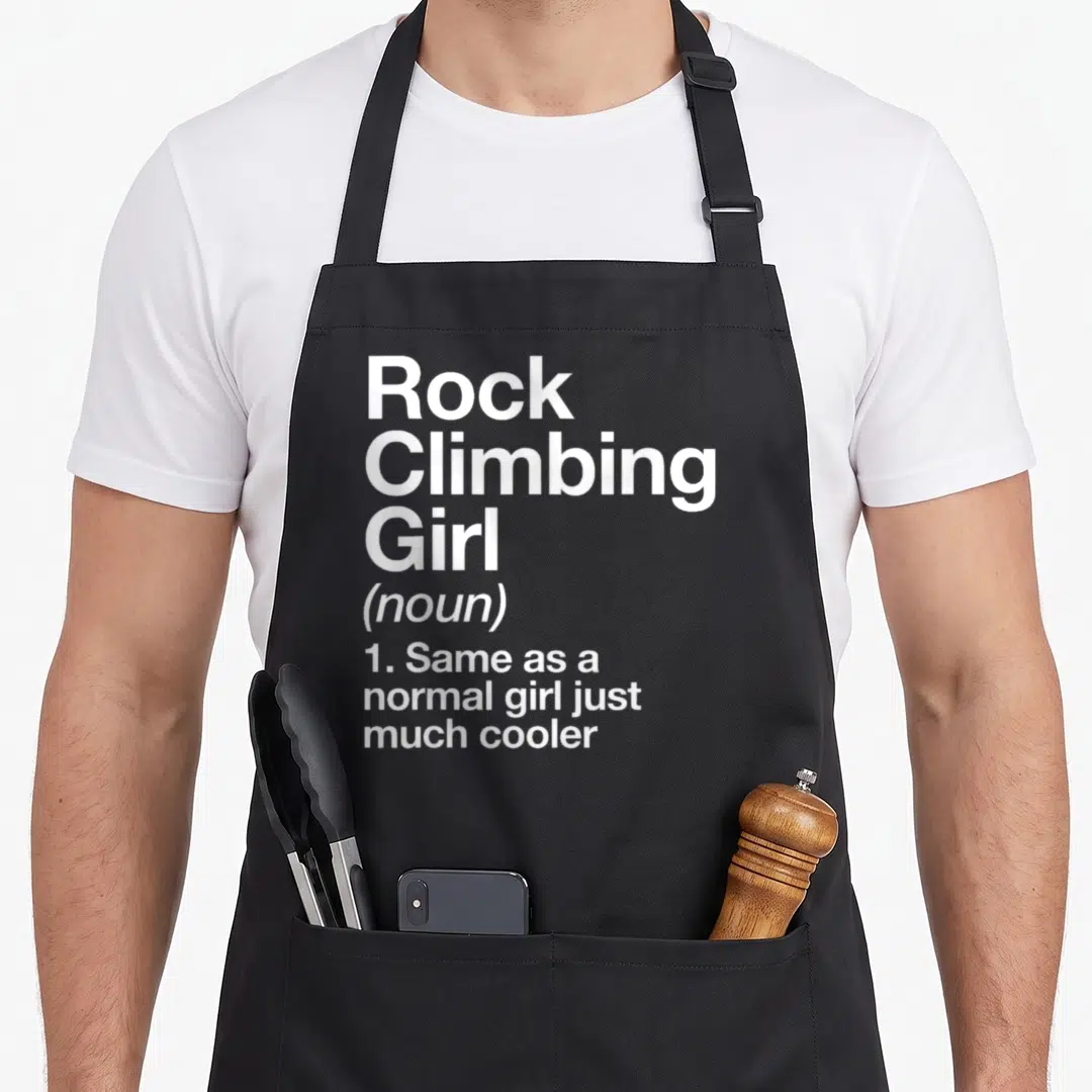 Rock sassy apron - White stacked text defining Rock Climbing Girl as a noun just much cooler — shown on a black cotton canvas apron against a white background