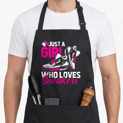 Sneaker streetwear apron - Just A Girl Who Loves Sneakers text with pink and white high-top sneakers and three hearts — shown on a black cotton canvas apron against a white background