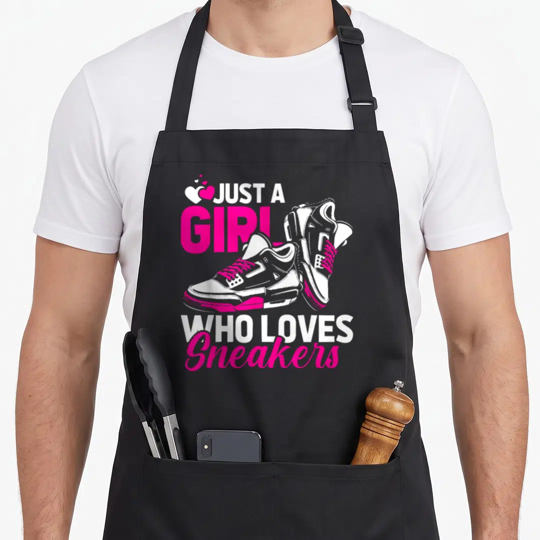 Sneaker streetwear apron - Just A Girl Who Loves Sneakers text with pink and white high-top sneakers and three hearts — shown on a black cotton canvas apron against a white background