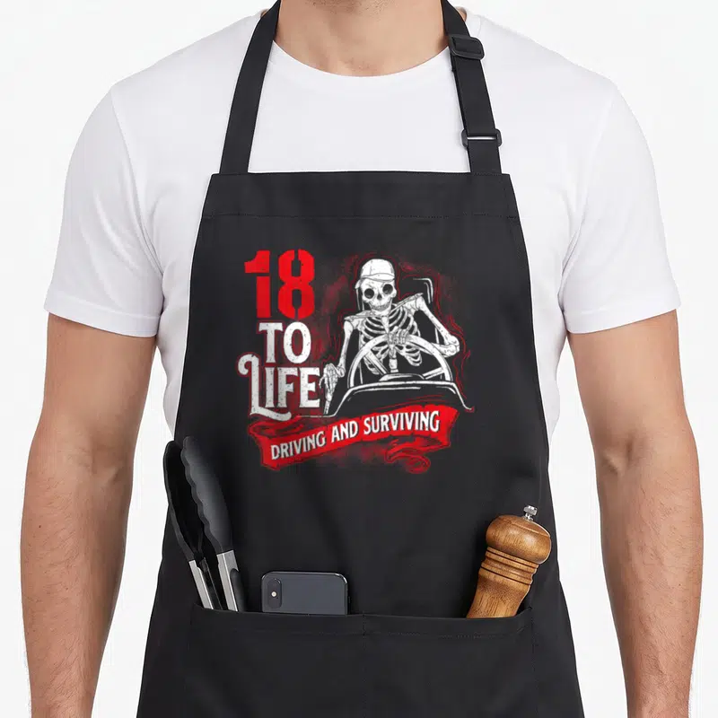 Rig trucking semi truck apron - Skeleton driver with 18 TO LIFE text and red banner — shown on a black cotton canvas apron against a white background