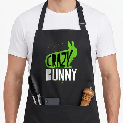 Wildlife bunny apron - Green bunny silhouette with black crazy text and white bunny lettering with splatters — shown on a black cotton canvas apron against a white background