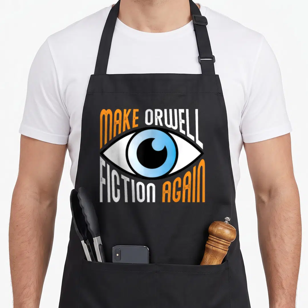 Orwell libertarian fiction apron - Eye graphic with Make Orwell Fiction Again text in orange white blue and black — shown on a black cotton canvas apron against a white background