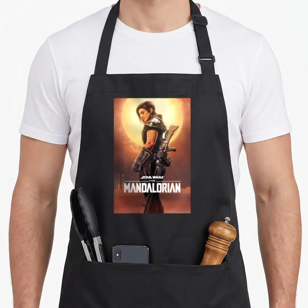 Poster dunes apron - Cara Dune in armor against yellow sun with white Star Wars The Mandalorian text — shown on a black cotton canvas apron against a white background