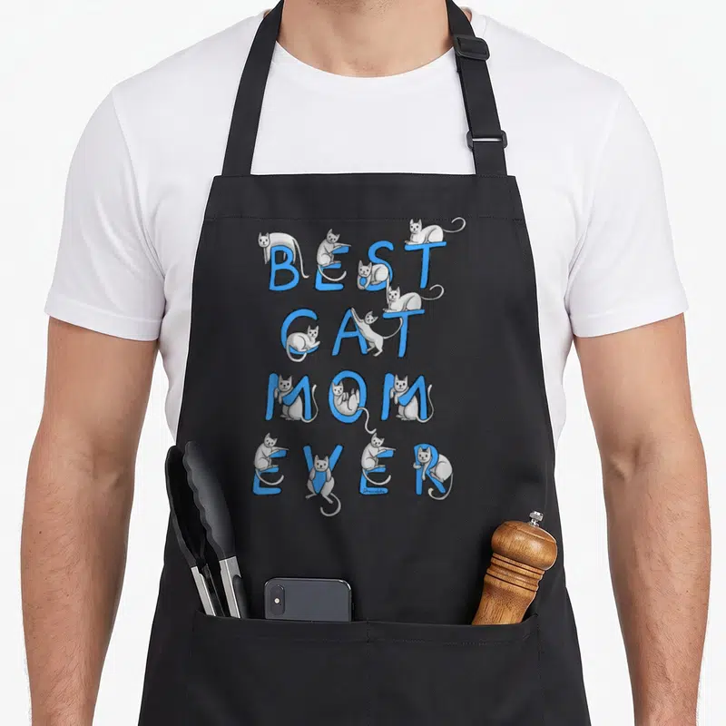 Cool kitten cat apron - Grey cartoon cats climbing on vertical blue letters reading BEST CAT MOM EVER — shown on a black cotton canvas apron against a white background