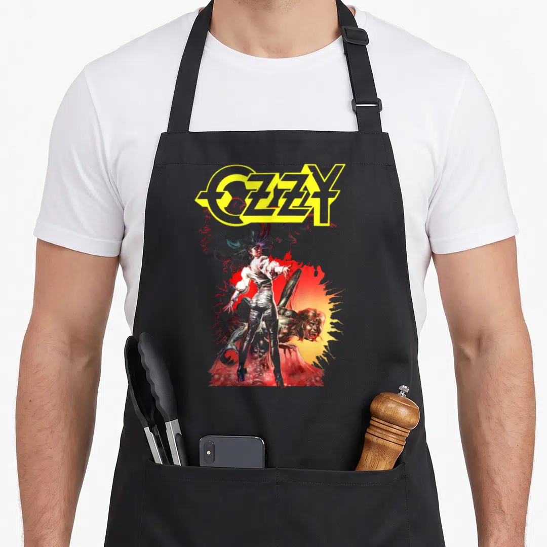 Ozzy ultimate apron - Cartoon person with spiky hair and OZZY text above crouching figure — shown on a black cotton canvas apron against a white background
