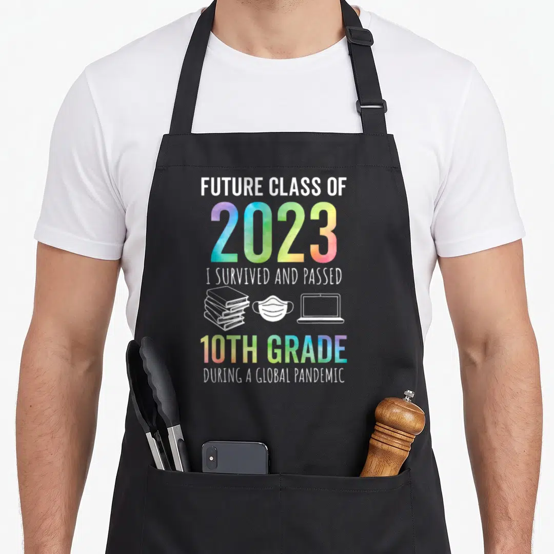 10th future class apron - Stacked text reading Future Class of 2023 10th Grade with books mask laptop icons in rainbow — shown on a black cotton canvas apron against a white background