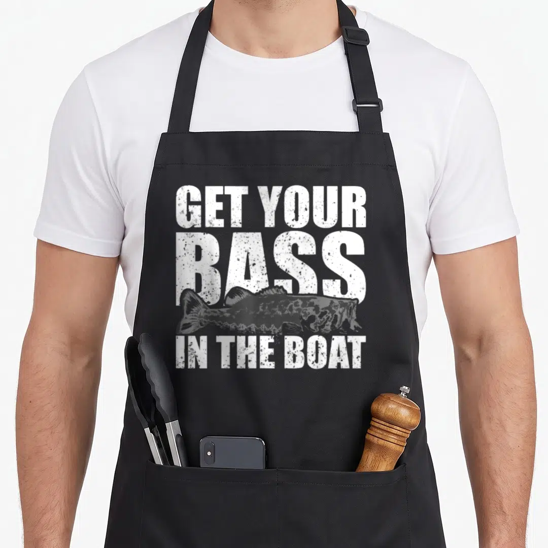 Boat fishing aprons - Distressed white text reading GET YOUR BASS IN THE BOAT with a horizontal grey bass fish — shown on a black cotton canvas apron against a white background