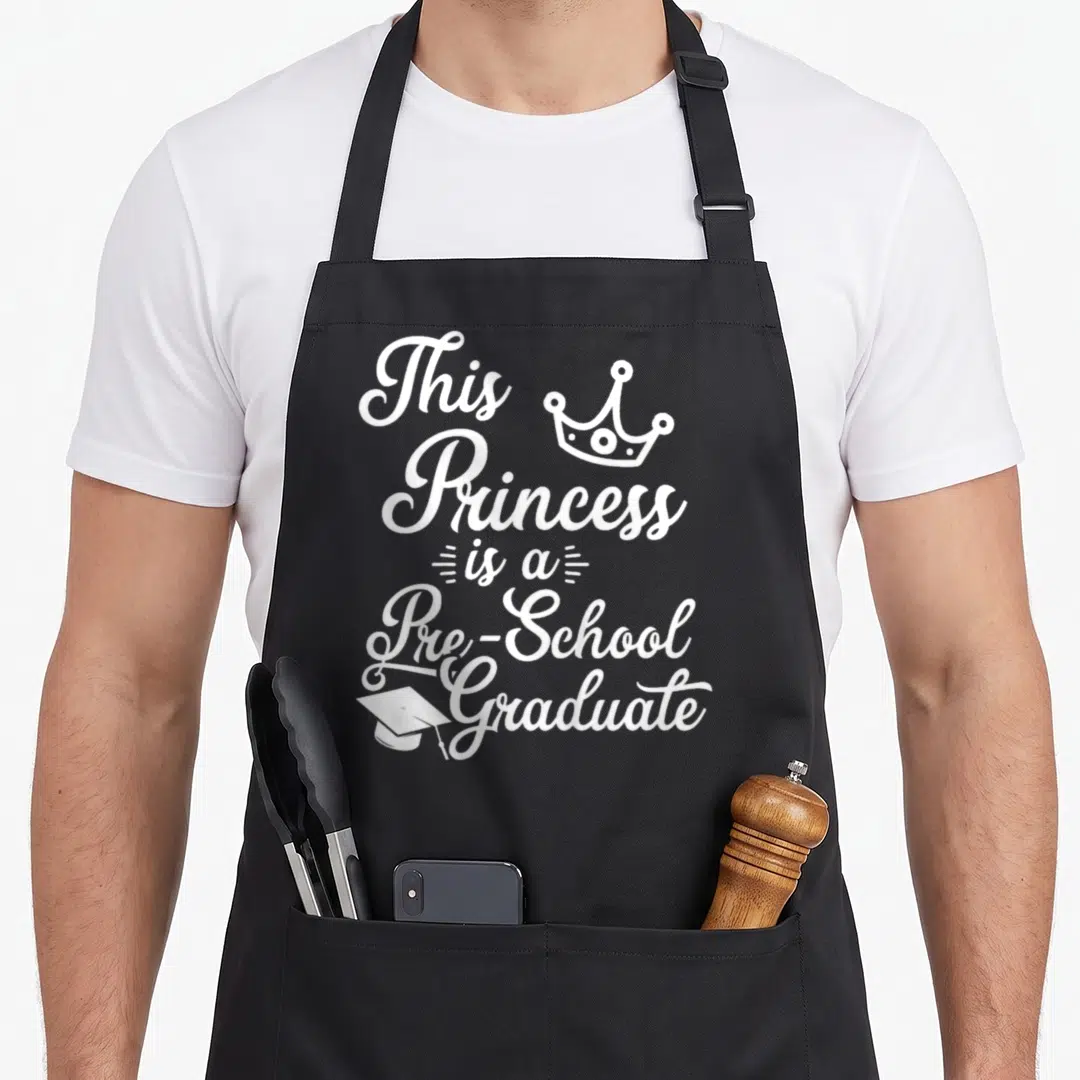 Pre school graduation apron - White cursive text reading This Princess is a Pre-School Graduate with crown and cap icons — shown on a black cotton canvas apron against a white background
