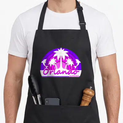 Tourist florida apron - Retro purple and pink sun with white palm trees, dolphins, and Orlando Florida text — shown on a black cotton canvas apron against a white background