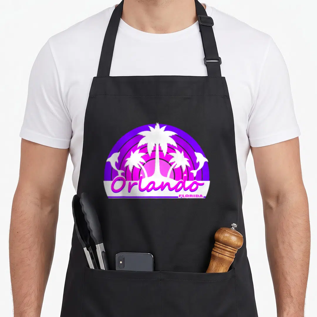 Tourist florida apron - Retro purple and pink sun with white palm trees, dolphins, and Orlando Florida text — shown on a black cotton canvas apron against a white background