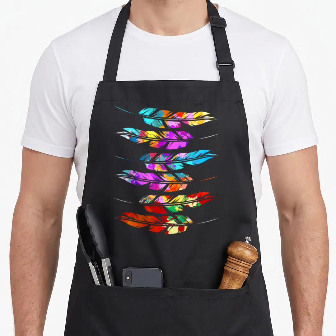 Feather colorful aprons - Six multicolored feathers in vertical watercolor stack with blue purple yellow orange red — shown on a black cotton canvas apron against a white background