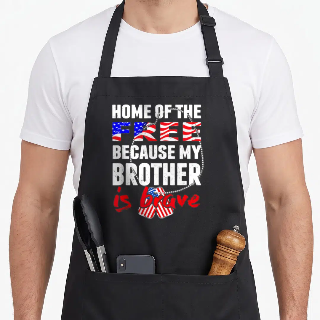 Brother grunt apron - Distressed text reading Home of the Free Because My Brother is brave with US flag heart and dog — shown on a black cotton canvas apron against a white background
