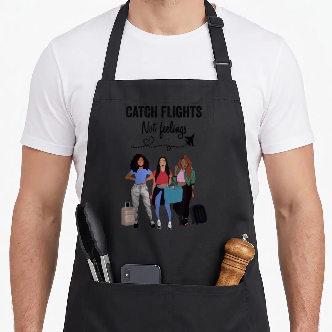 Feeling summer aprons - Three women with suitcases and dotted airplane trail below text — shown on a black cotton canvas apron against a white background