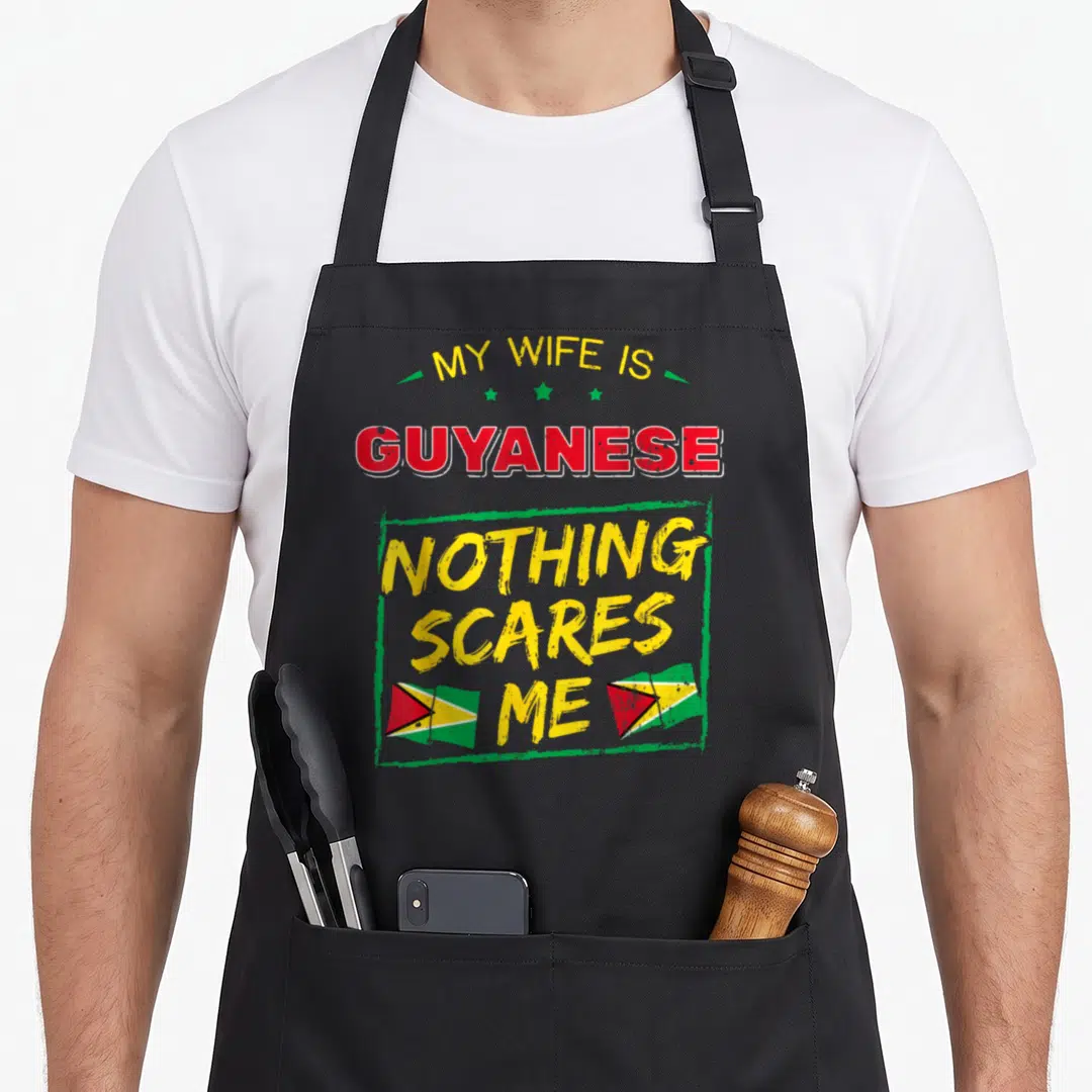 Guyanese wife apron - Stacked text reading My Wife Is Guyanese Nothing Scares Me with two flags — shown on a black cotton canvas apron against a white background