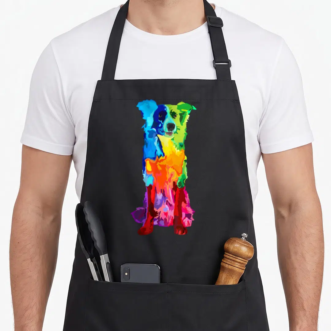 Colorful border collie apron - Multicolored cartoon border collie in blue, green, yellow, orange, red, and purple — shown on a black cotton canvas apron against a white background