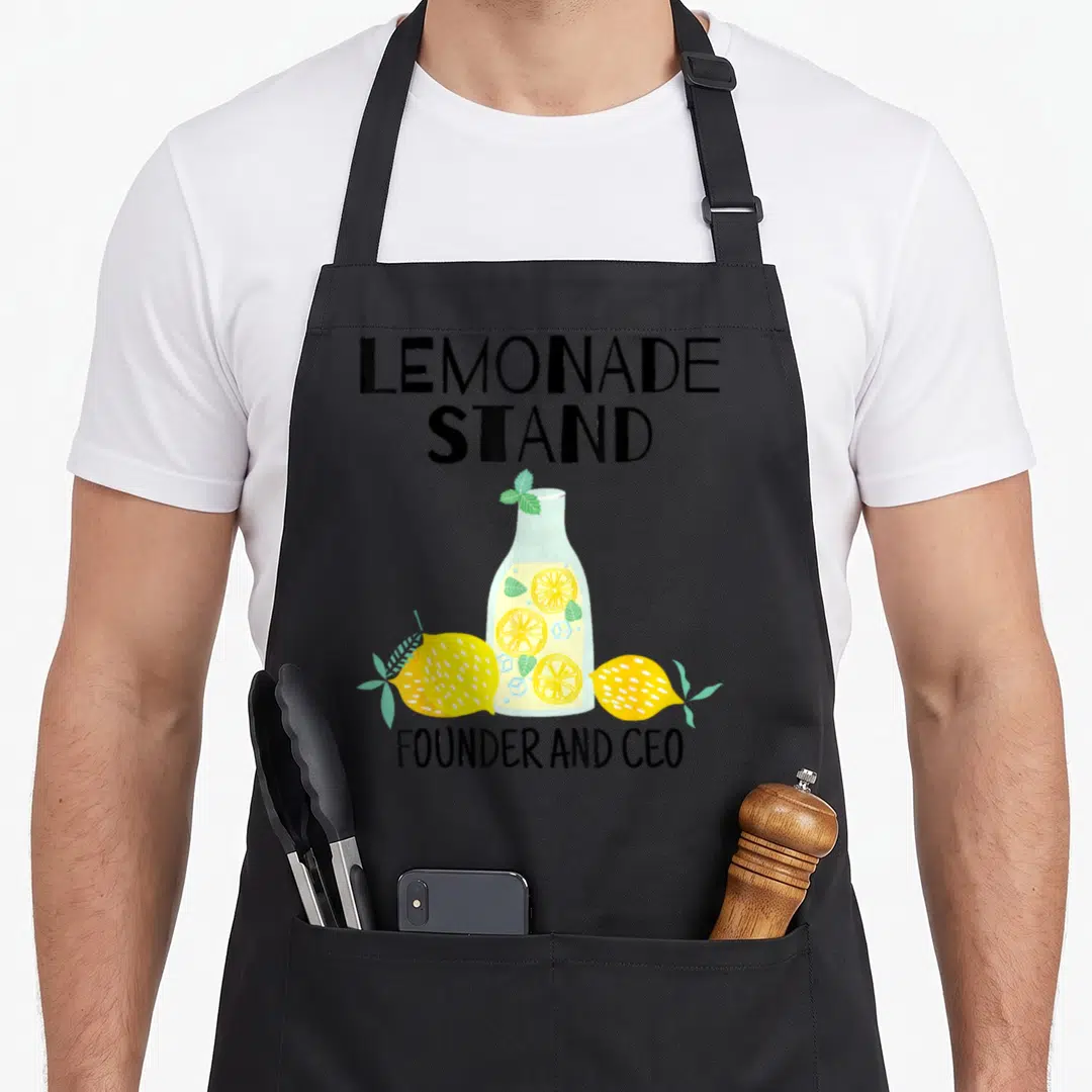 Founder ceo lemonade apron - Cartoon lemonade bottle with two lemons and founder ceo text in yellow and green — shown on a black cotton canvas apron against a white background