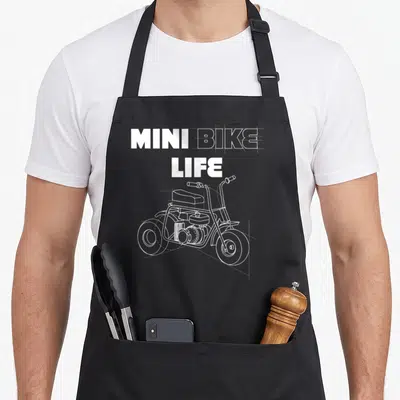 Minibike bike apron - MINI BIKE LIFE text above white line-art mini bike drawing on black apron — shown on a black cotton canvas apron against a white background