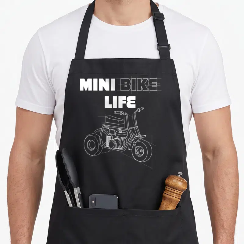 Minibike bike apron - MINI BIKE LIFE text above white line-art mini bike drawing on black apron — shown on a black cotton canvas apron against a white background