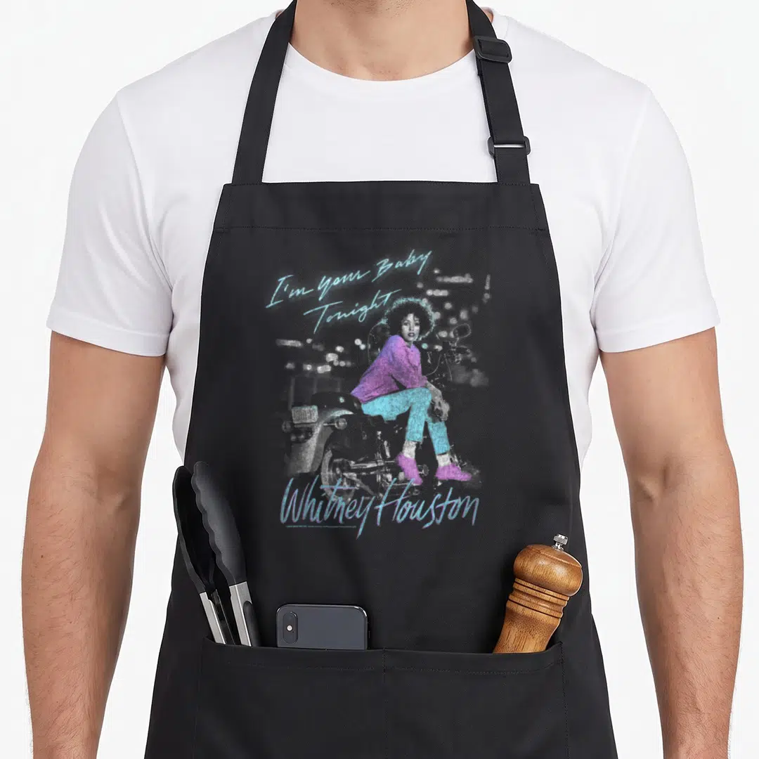 Baby houston problem apron - Whitney Houston sitting on motorcycle with blue and purple script text I'm Your Baby — shown on a black cotton canvas apron against a white background