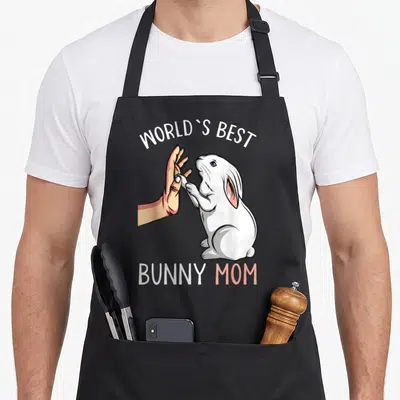 Funny rabbit easter bunny aprons - Cartoon white bunny high-fiving human hand with World's Best Bunny Mom text — shown on a black cotton canvas apron against a white background