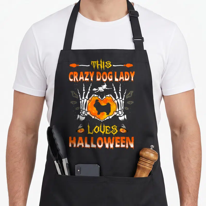 Tzu halloween dog apron - Skeleton hands holding orange heart with Shih Tzu silhouette, witch flying, Halloween text — shown on a black cotton canvas apron against a white background