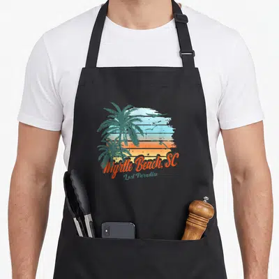 Lost south beach apron - Retro Myrtle Beach design with two palm trees, three birds, and striped sunset background — shown on a black cotton canvas apron against a white background
