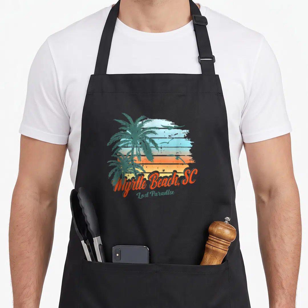 Lost south beach apron - Retro Myrtle Beach design with two palm trees, three birds, and striped sunset background — shown on a black cotton canvas apron against a white background