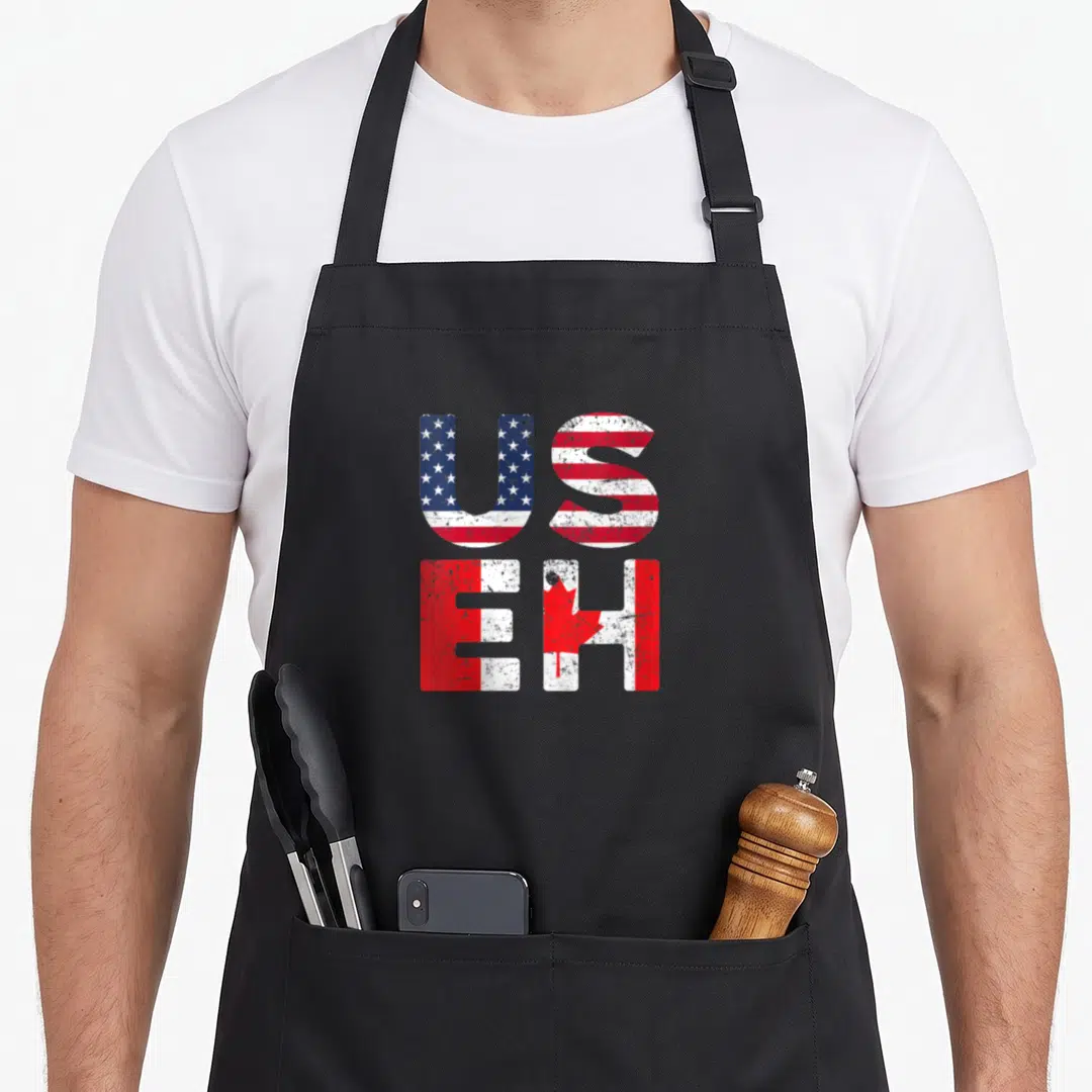 Flag useh pride apron - Stacked US and EH letters filled with USA and Canada flag patterns in distressed red white blue — shown on a black cotton canvas apron against a white background