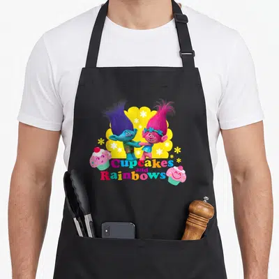 Troll cupcake apron - Two trolls holding hands with Cupcakes and Rainbows text and smiling cupcakes on yellow scalloped — shown on a black cotton canvas apron against a white background