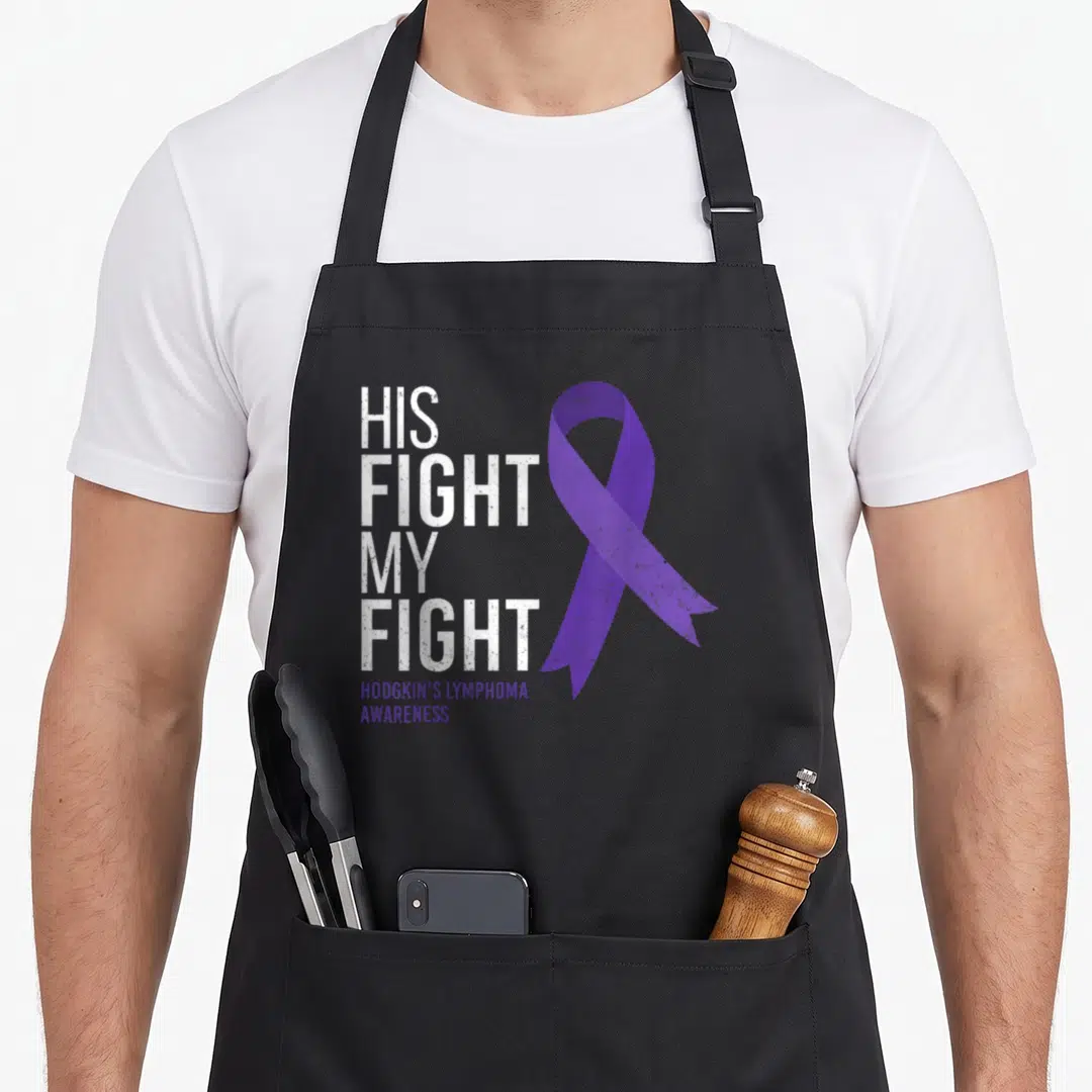 His lymphoma awareness apron - Stacked white text reading His Fight My Fight beside a large purple awareness ribbon — shown on a black cotton canvas apron against a white background