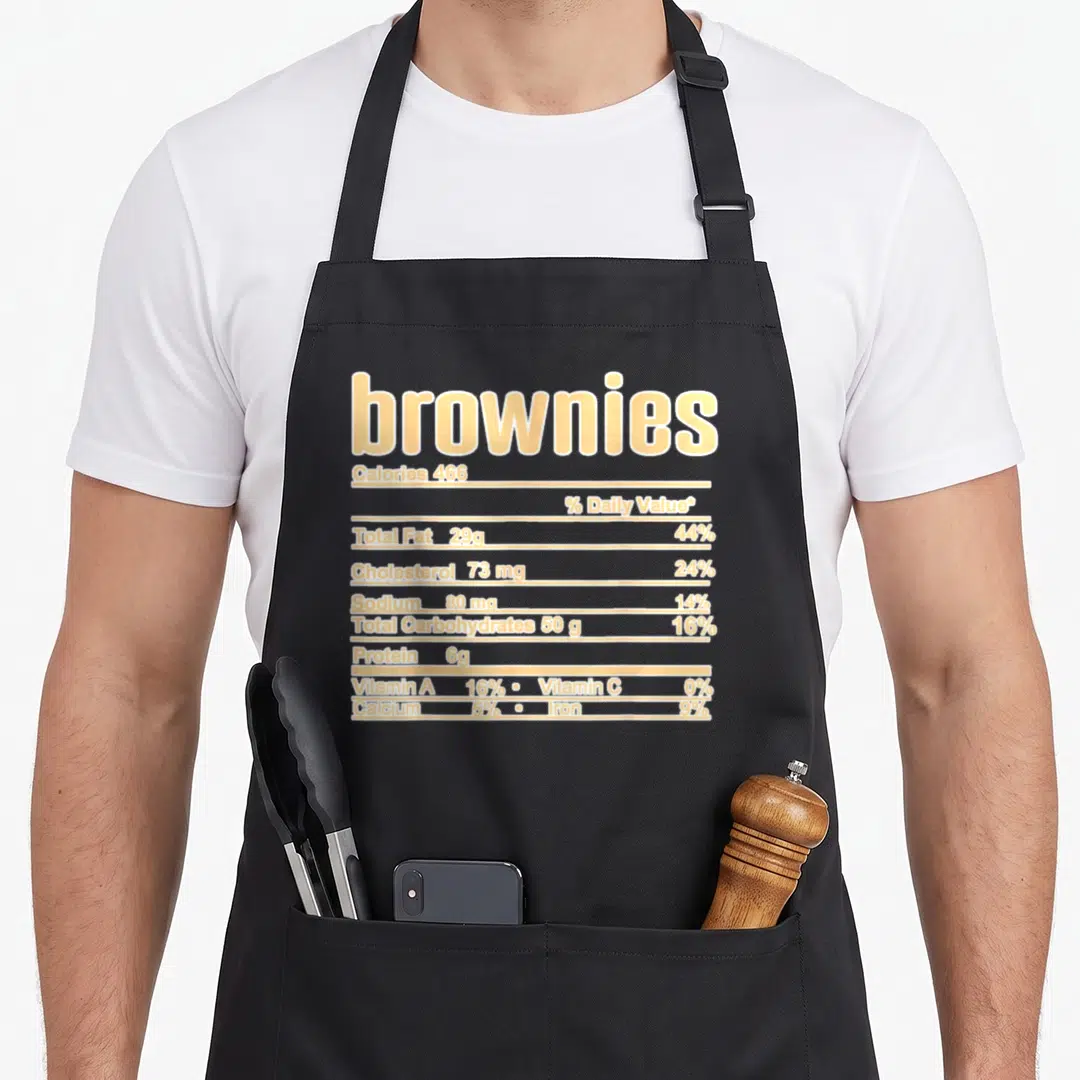 Browny christmas apron - beige nutrition facts label for brownies with calorie and fat data — shown on a black cotton canvas apron against a white background