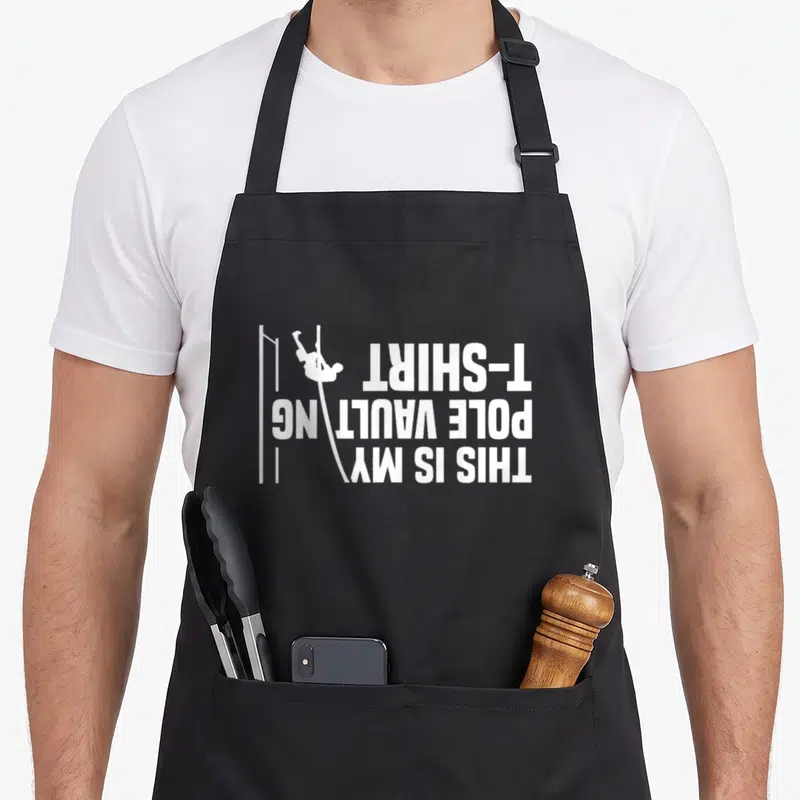 Vaulting track apron - White rotated text THIS IS MY POLE VAULTING T-SHIRT with minimalist pole vaulter silhouette — shown on a black cotton canvas apron against a white background