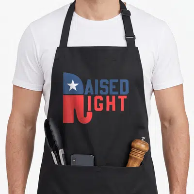Republican elephant print apron - Raised Right text design with star in R and elephant trunk R shape in red and blue — shown on a black cotton canvas apron against a white background